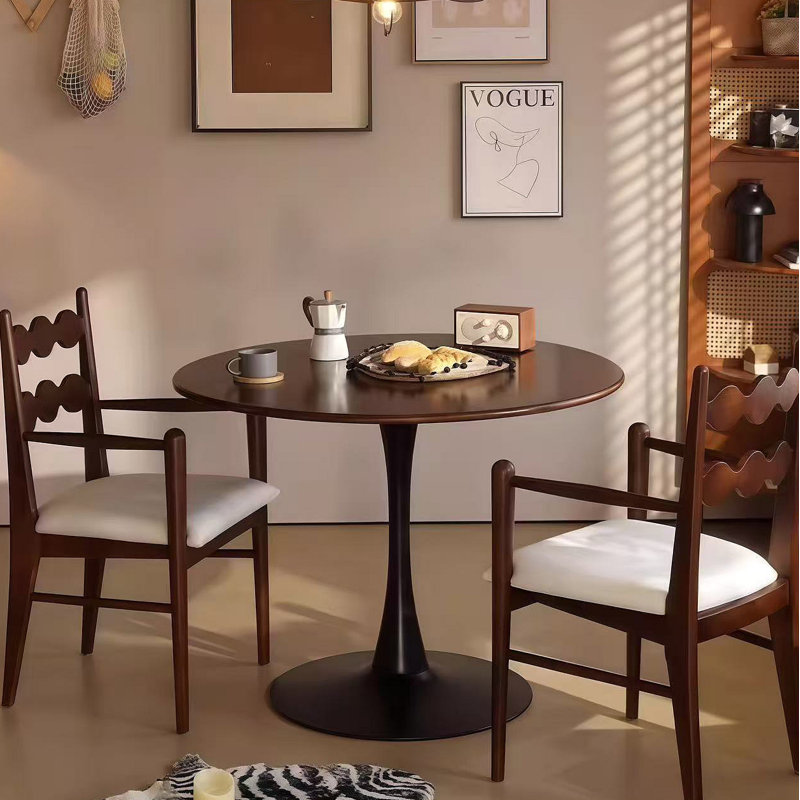 Une table de salle à manger ronde de luxe légère avec grain de bois profond, une élégante base en acier en forme de tulipe et un plateau de table en panneau de fibres à densité moyenne dans un style médiéval moderne
