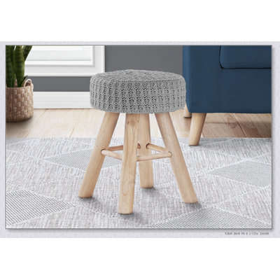 Repose-pieds rond luxueux en velours gris avec pieds en bois naturel, parfait pour le confort et le style de tout salon.