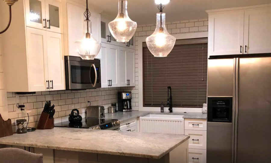 White kitchen cabinets with black hardware and pendant lighting.
