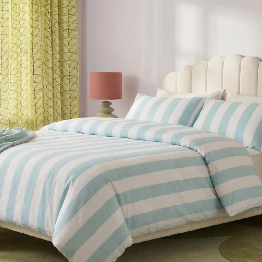 Beige platform bed with sage green bedding.