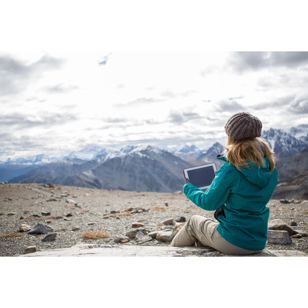 Wanderer auf dem Gipfel eines Berges mit digitalem Tablet von Swissmediavision - Kunstdrucke ohne Rahmen auf Leinwand