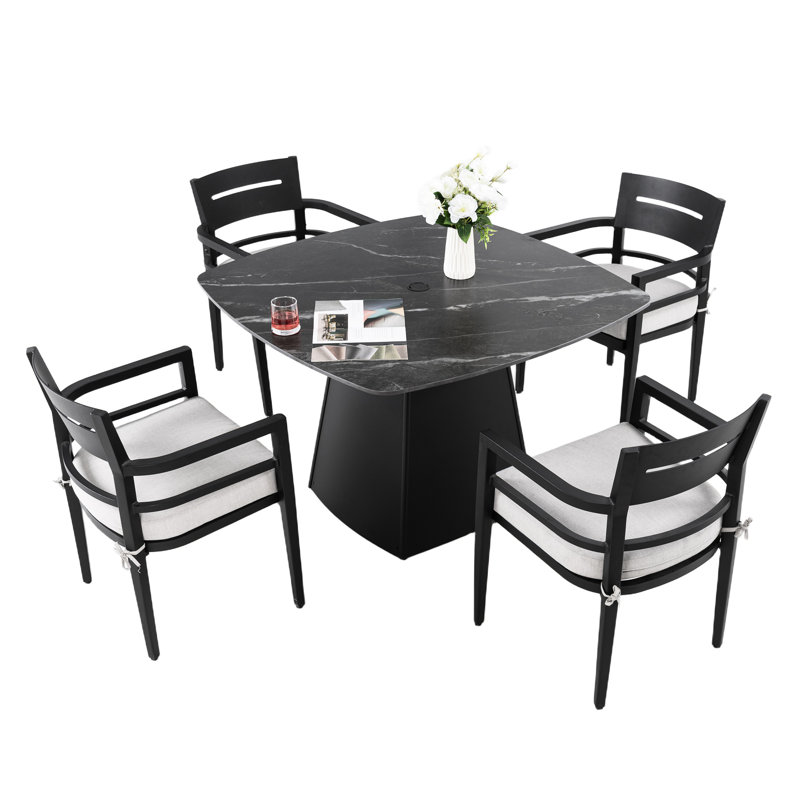 Ensemble de salle à manger d'extérieur 5 pièces, table en pierre frittée de 112 cm, fauteuils, coussins dégradés, patio moderne avec structure carrée arrondie et aspect rouille.