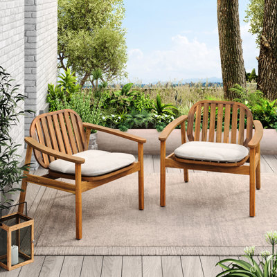 Deux fauteuils club avec coussins beiges, structure en bois, pieds en eucalyptus, dossier incurvé et panneaux à lattes, pour profiter du jardin. Deux fauteuils au design moderne et élégant, légèrement inclinés, convenant aux patios et aux jardins.