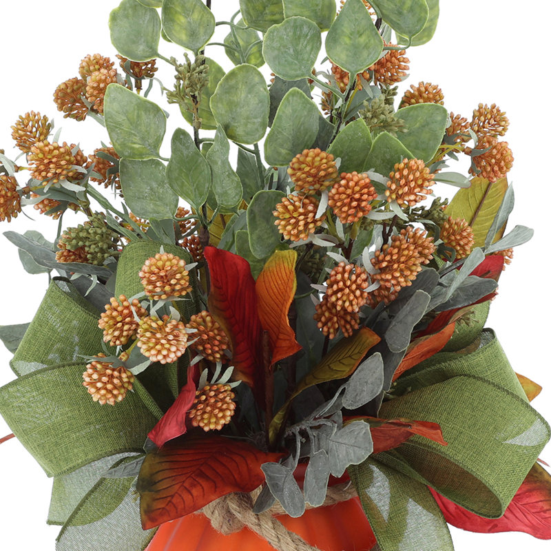 Centre de table d'automne avec eucalyptus et baies chanceuses dans un vase de citrouille