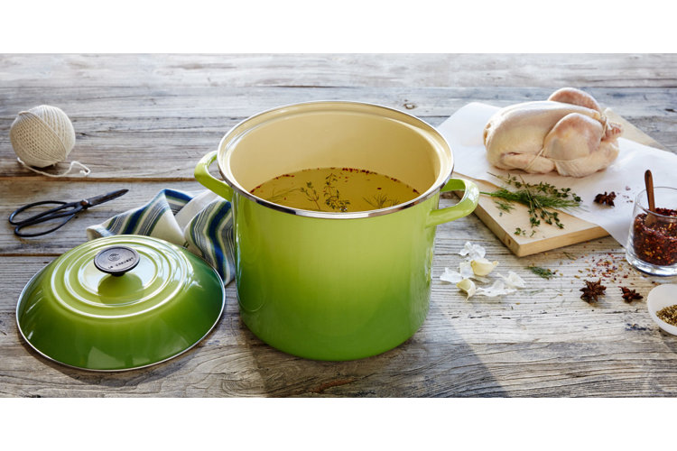 a green Le Creuset soup pot with a thin chicken soup in it