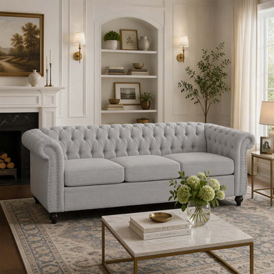 Canapé 3 places de style Chesterfield avec capitonnage à boutons, clous décoratifs et accoudoirs sculptés pour des espaces de vie élégants.