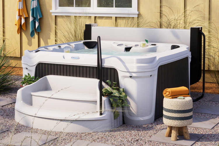 white hot tub with a cover, stairs, and a rattan stool with a towel