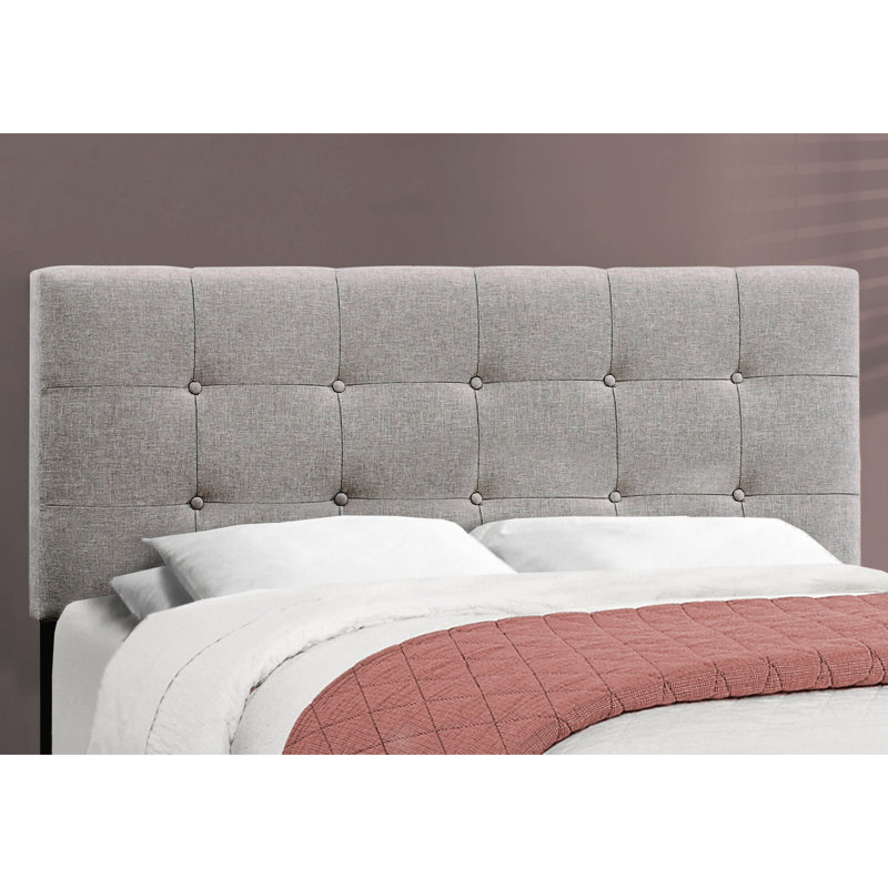 Lit tapissier grand format gris, créant une chambre luxueuse avec des pieds en plastique noir stable