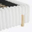 Lit tapissier élégant avec tête de lit ondulée et coutures verticales, idéal pour créer une chambre à coucher confortable et élégante