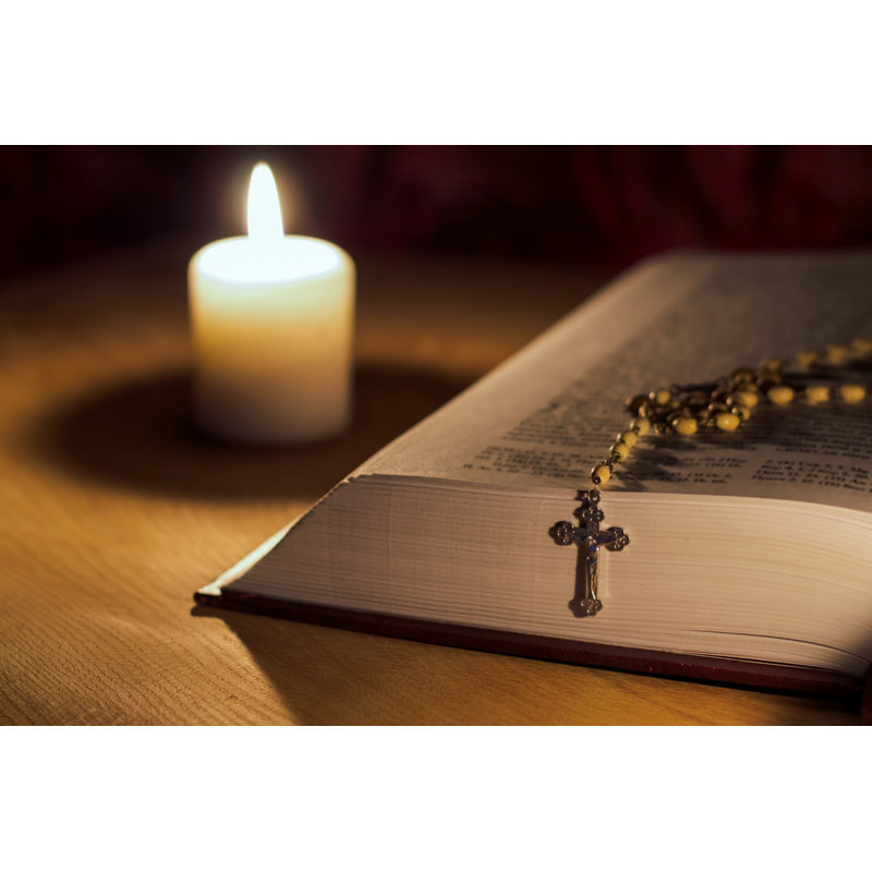 A Burning Candle, A Bible And A Cross A Rosary On A Wooden Table by Osobystist - Wrapped Canvas Print