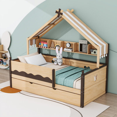 Lit plateforme en bois en forme de maison avec étagères, auvent en tissu et lit gigogne.