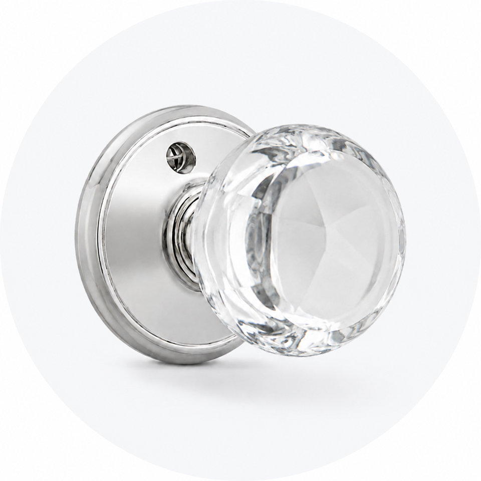 Polished chrome door knob with a round, faceted clear glass handle against a light gray circular background.