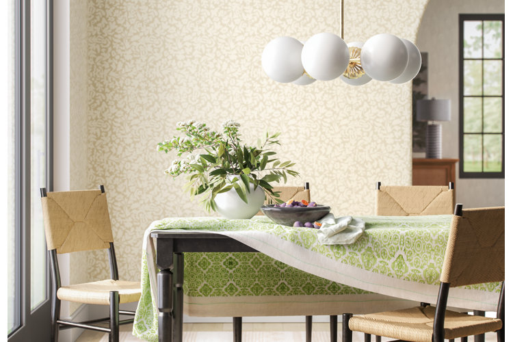 green geometric tablecloth on a dining table, styled with a white table vase full of flowers and a bowl of figs