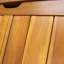 Coffre de terrasse spacieux en bois d'acacia avec ventilation à lattes, couvercle à charnières et construction résistante aux intempéries pour le rangement extérieur.