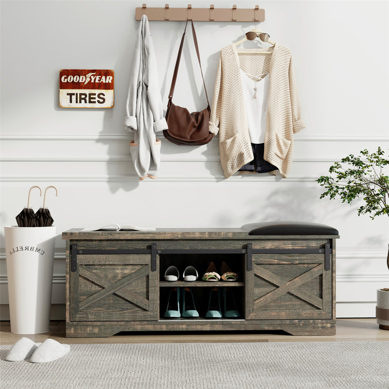 Le banc de litière à porte de grange coulissante de 47 pouces de style campagne moderne avec porte d'entrée de grange avec découpe d'entrée et fonctionnalité de banc à chaussures combine style et solutions de rangement pratiques.