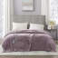 Mauve electric blanket with two hand-held controllers draped over a bed
