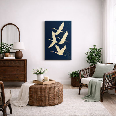Grues gracieuses volant sur un fond bleu profond avec des accents dorés - reproduction d'art sur toile encadrée
