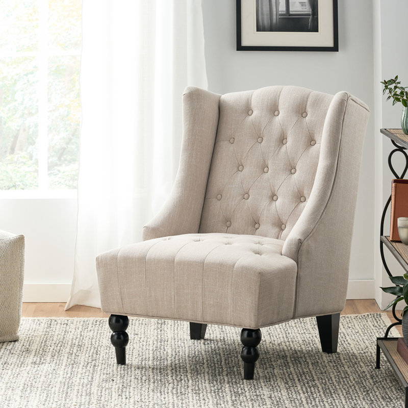 Fauteuil à oreilles beige avec capitonnage à boutons et structure en bois de bouleau robuste et élégante