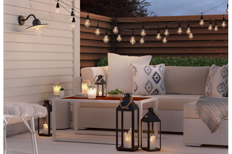 Apartment balcony furniture idea with an L-shaped sectional, featuring a wicker frame and white cushions.