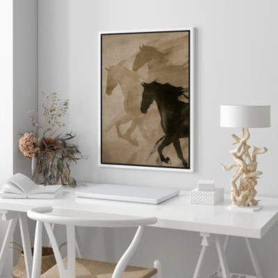 Wall art print in a white floater frame featuring silhouettes of three horses in tan and black on a neutral background.