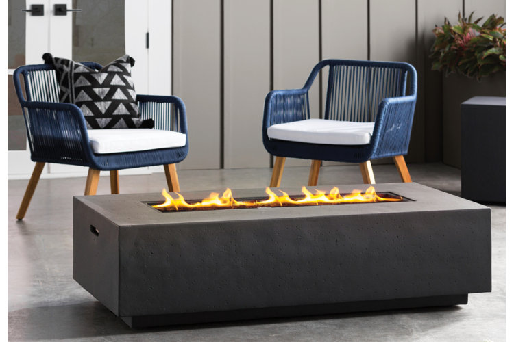Modern rectangular fire table with flames, flanked by two blue accent chairs