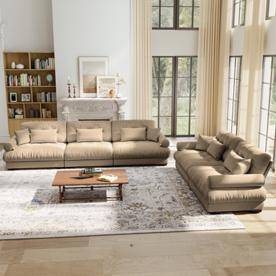 Un ensemble de canapés modulaires combinant un canapé deux places et un canapé trois places, en velours, avec coussins décoratifs, coussins lombaires et accoudoirs arrondis. Disponible en couleur chameau, idéal pour les salons et les appartements.