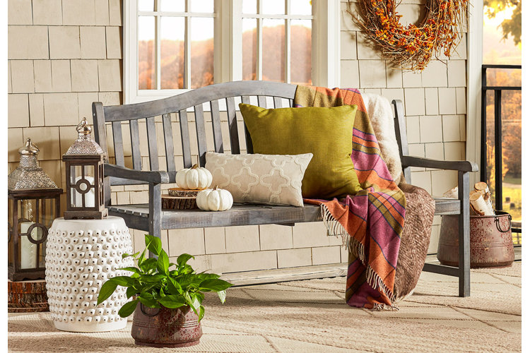 front porch with a teak bench, colorful fall pillows, and a potted plant