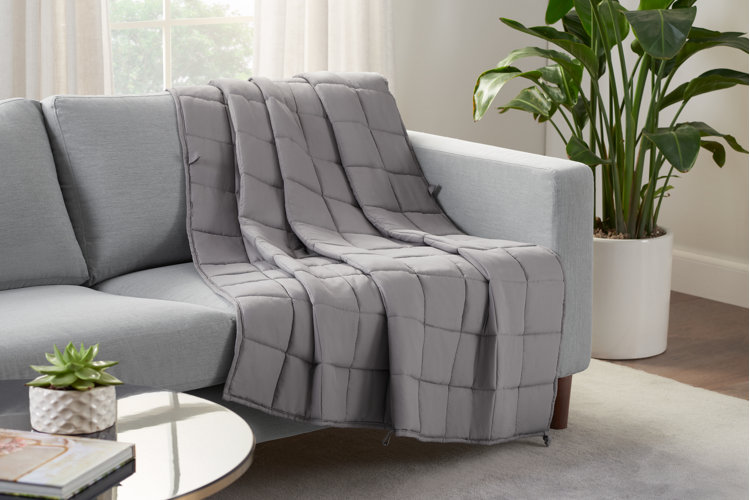 gray weighted blanket draped over a sofa