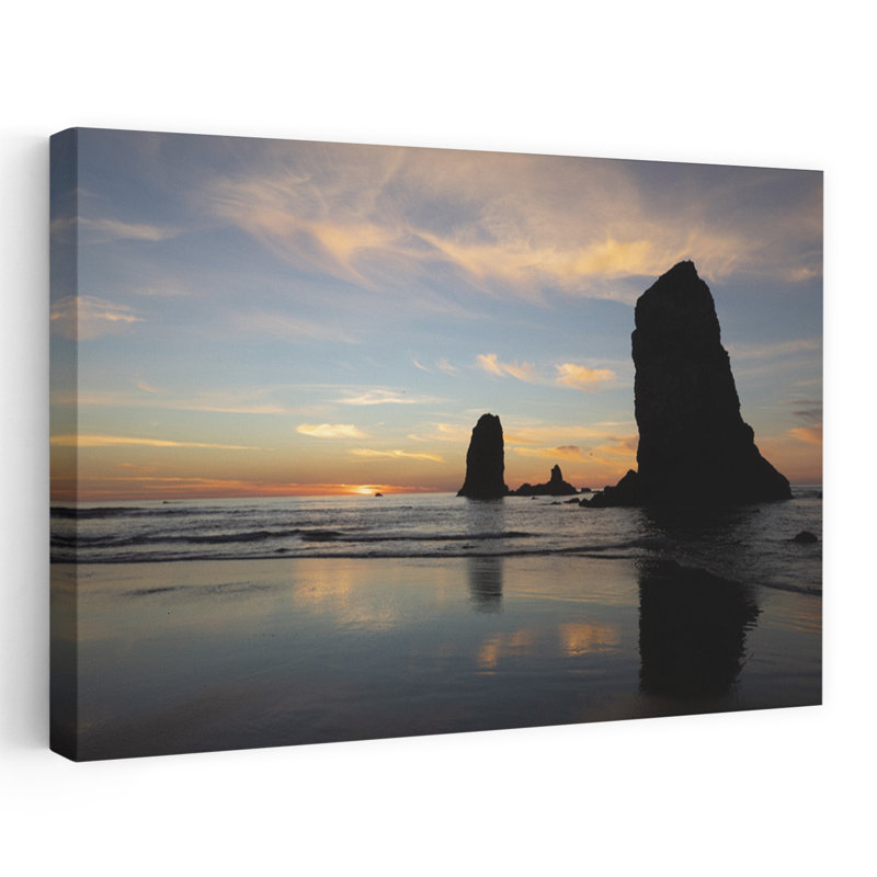 Silhouettes Of Rock Formations At Sunset At Cannon Beach Oregon USA by Dan Merkel - Wrapped Canvas Print
