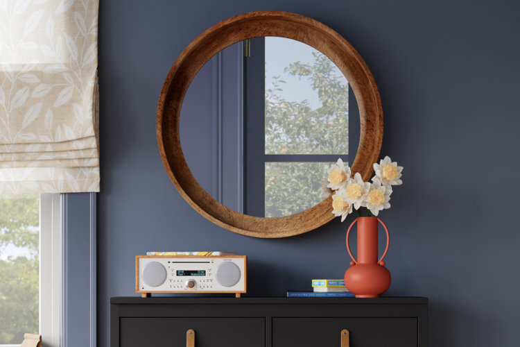 modern entryway with a round wall mirror over a black shoe storage cabinet