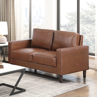 Canapé deux places d'inspiration industrielle, recouvert de similicuir au chocolat, avec rembourrage en mousse et pouvant supporter jusqu'à 136 kg. Style contemporain. Ressorts ensachés. Pieds en bois apparents.