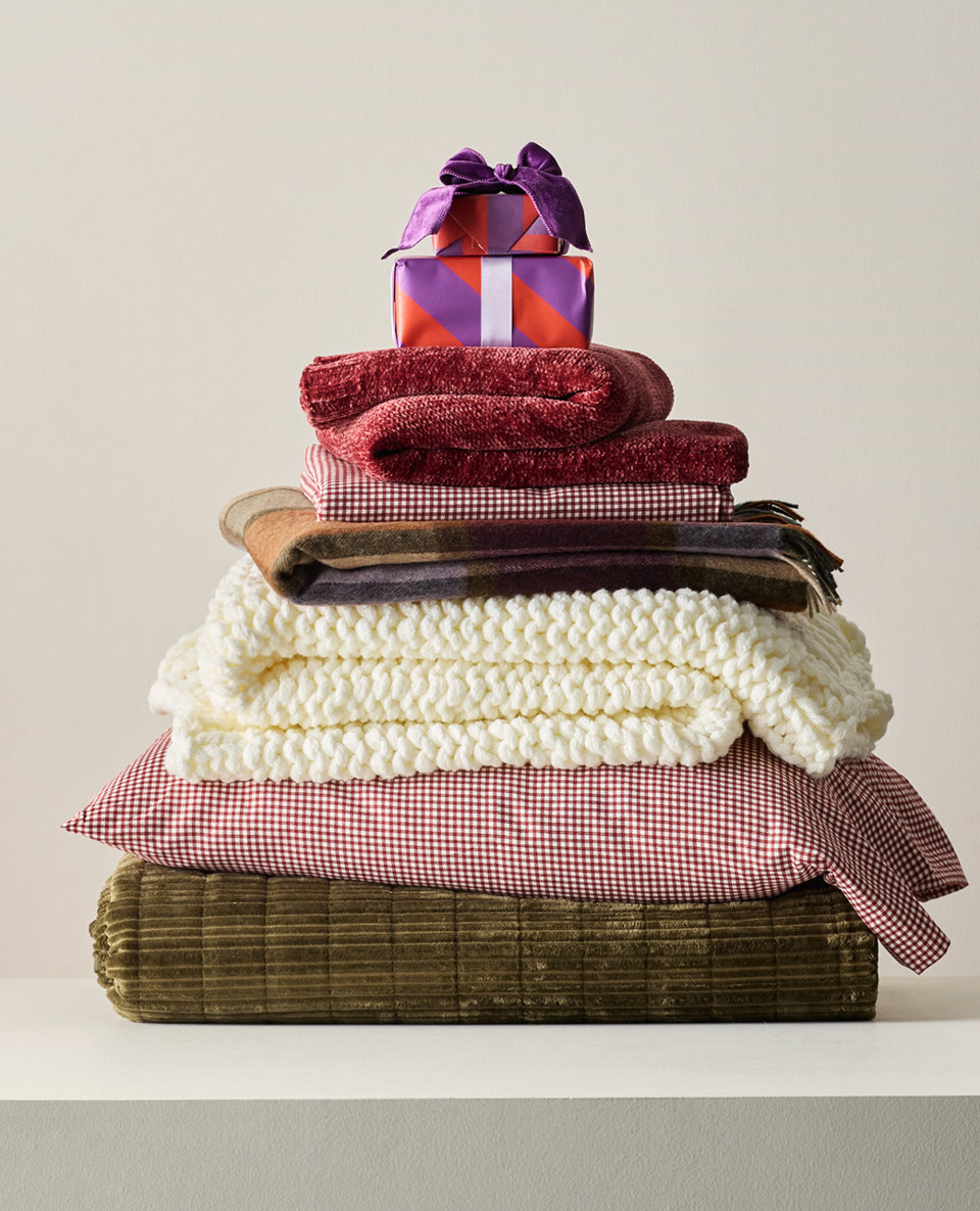 Stack of blankets, pillows, and a gift.