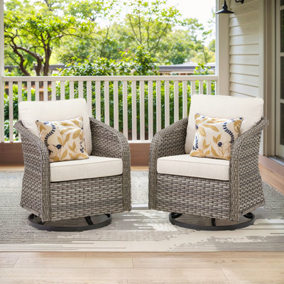 Ensemble de 2 fauteuils à bascule pivotants d'extérieur en résine tressée, avec coussins beiges, pour véranda ou jardin.
