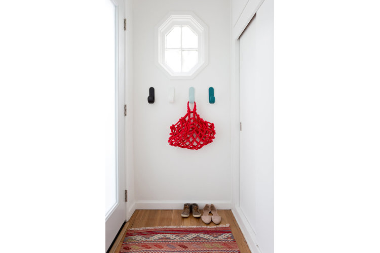 A sleek minimal entryway with colorful wall hooks.