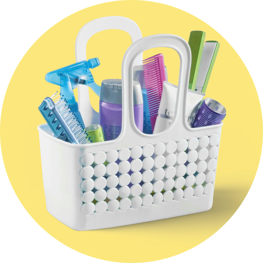A white plastic bath caddy filled with colorful toiletries and hair tools against a yellow circular background.