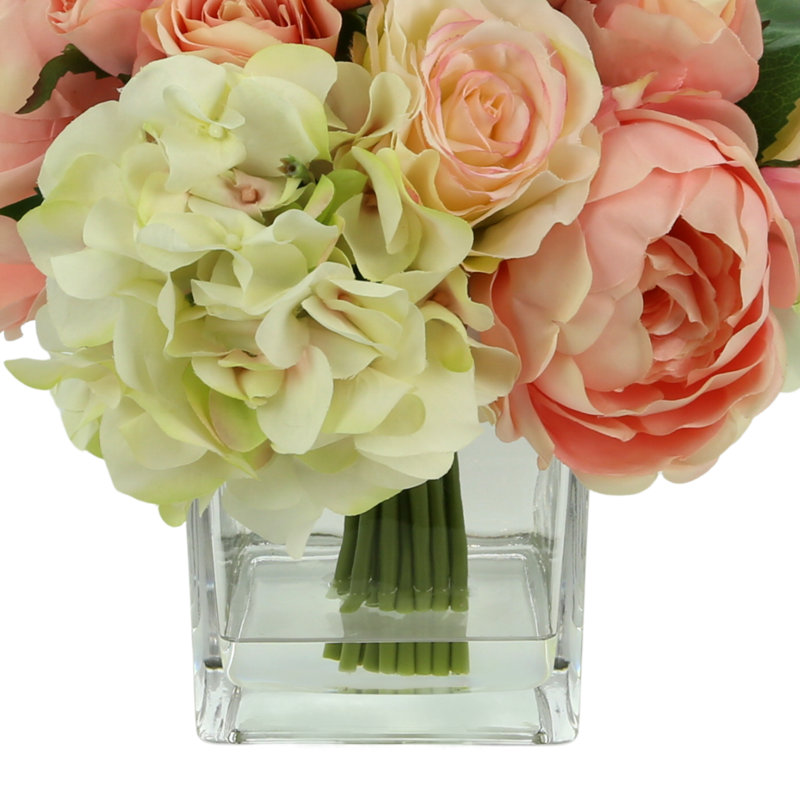 Arrangement de roses et de pivoines dans un vase en verre