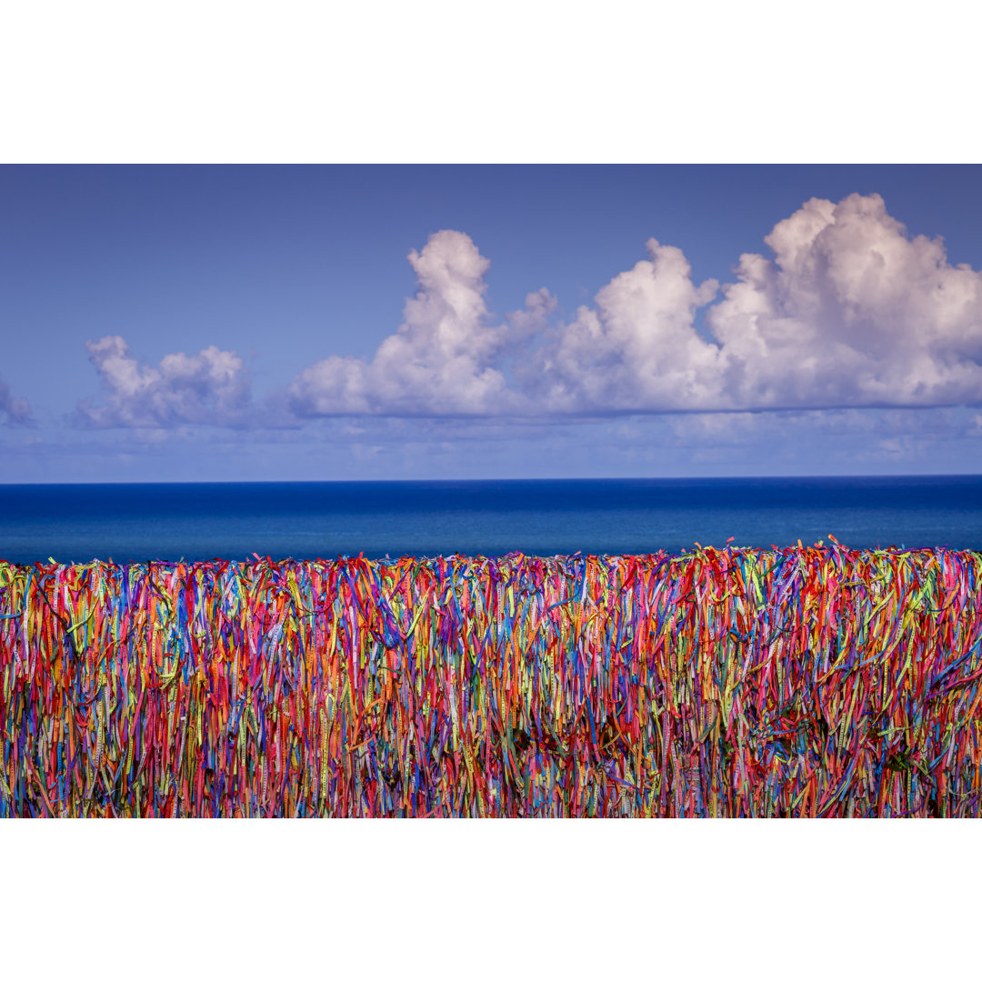 Bunte Bonfim-Wunschbänder an einer Wand und Strand in Porto Seguro - Bahia, Brasilien von Agustavop - Ohne Rahmen auf Le...