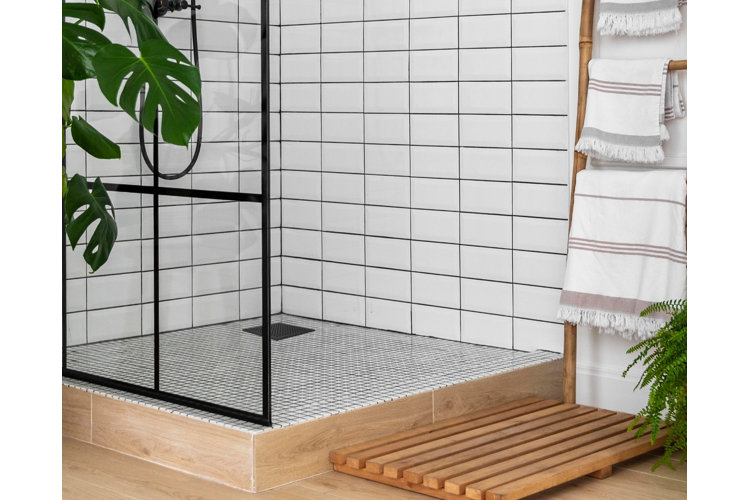modern white bathroom with glass shower. Wood bath mat with a blanket ladder filled with white towels