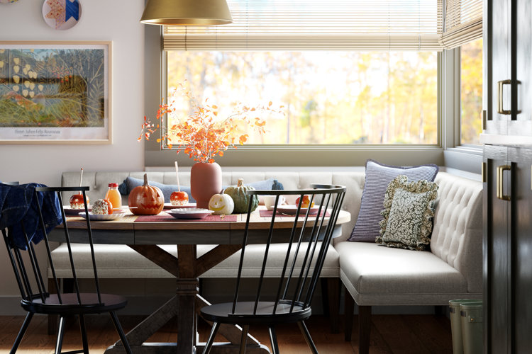 L-shaped breakfast nook with decorative pumpkins and a fall foliage arrangement on the table.