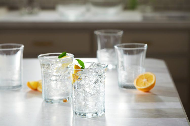 White countertop with clear glassware set with sparkling water and fruit slices