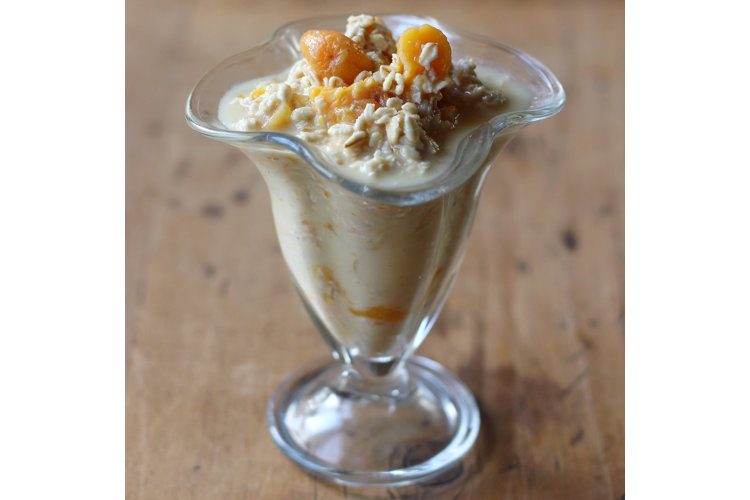 Close-up of glass cup with orange, lime and apricot oats.