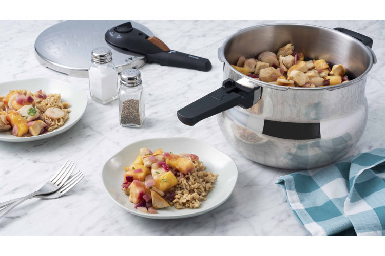 Large silver stovetop pressure cooker from which food is being served.
