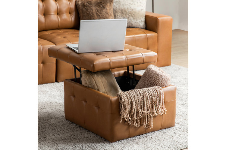 A rectangular genuine leather storage ottoman in a rich cognac brown with deep button tufting on the seat and a sturdy, lift-top storage lid