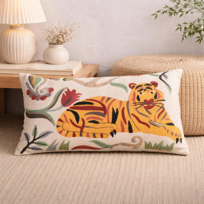 Coussin lombaire rectangulaire orné d'un tigre au repos et de broderies florales Aari, en tissu de coton flammé crème, avec garniture en polyester et fermeture éclair invisible, idéal pour une décoration intérieure bohème et éclectique.