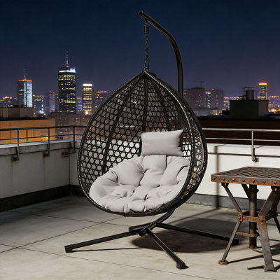 Chaise hamac robuste avec support, tissage en rotin durable et coussin amovible pour une utilisation intérieure et extérieure.