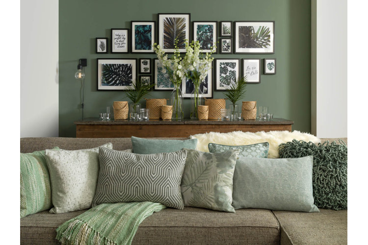 green living room wall filled with a gallery wall of art and prints with botanical and plant themes 