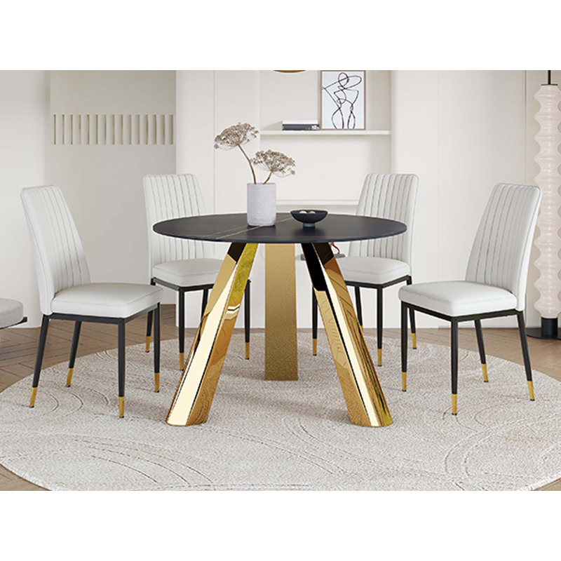 Une table de salle à manger ronde de 42 pouces avec un plateau en granit et des pieds en acier inoxydable, jumelée à quatre chaises de salle à manger en polyuréthane
