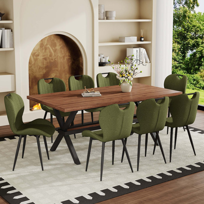 Table de salle à manger en panneau de fibres à densité moyenne noyer avec structure en X et huit chaises en tissu vert olive avec poignées intégrées pour une mobilité sans effort et des sièges polyvalents.
