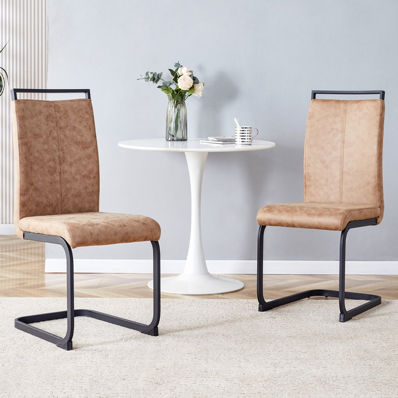 Élégantes chaises de salle à manger rembourrées à haut dossier avec pieds en tube de métal en forme de C, parfaites pour les sièges modernes et polyvalents.