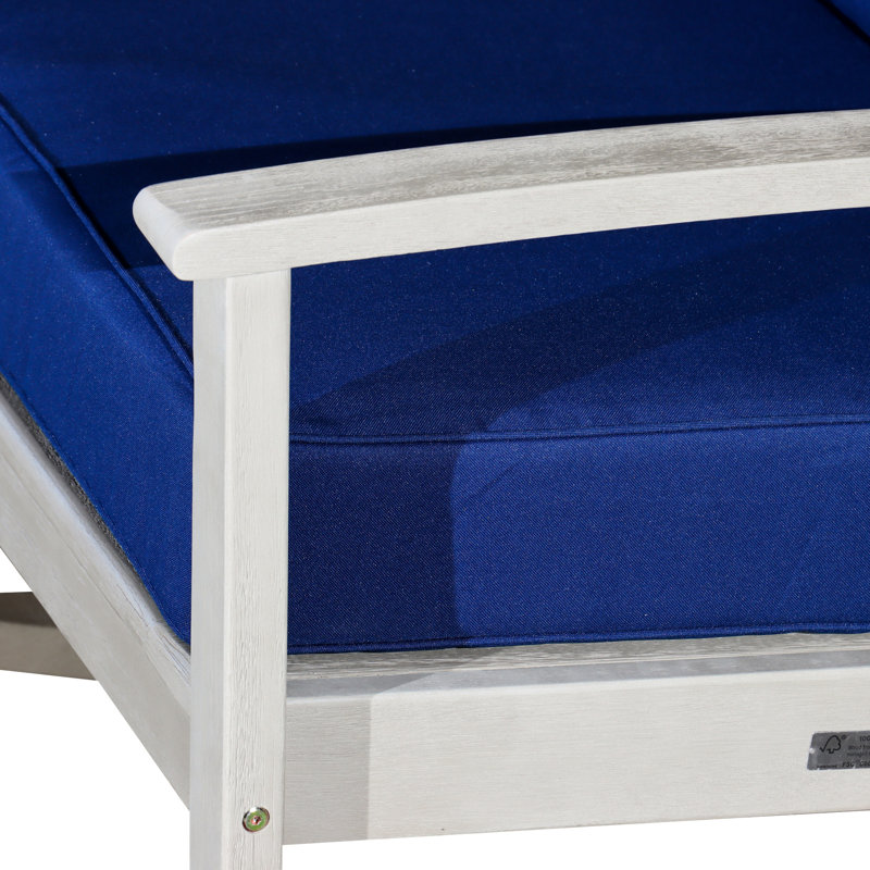 Chaise berçante en eucalyptus avec coussins bleu marine décontractés, surface grise en bois flotté pour un patio luxueux